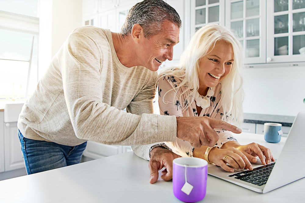 Young couple sitting at laptop smiling at each other